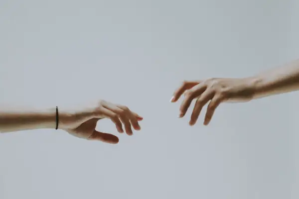 Two hands reaching out for one another from the left and right side of the image