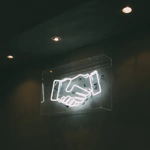 A white neon sign representing two hands being shaken