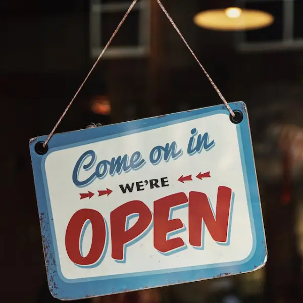A sign saying "Come on in, we're open" representing a website as a customer service strategy