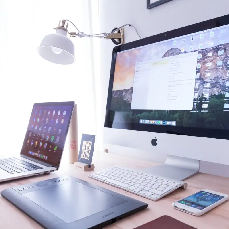 An iMac, iPhone, MacBook, and Wacom tablet on a table