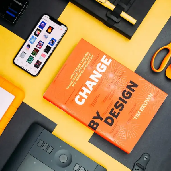 Tim Brown's book "Change by Design" on a desk besides an iPhone and other items.