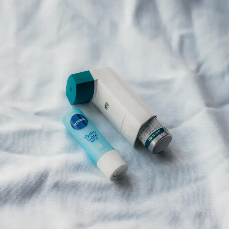 A lip balm beside an asthma inhaler