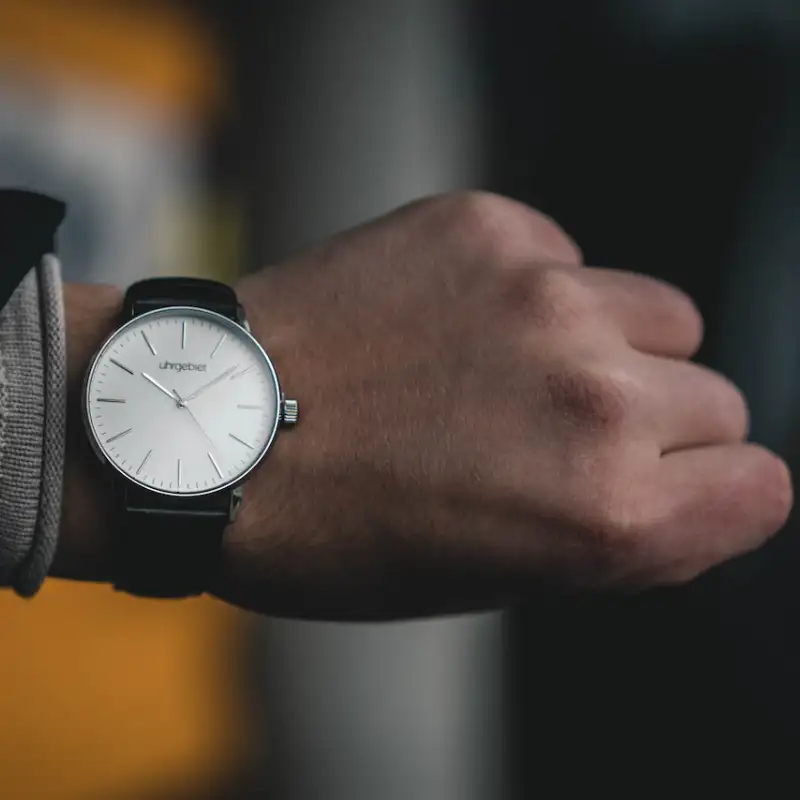 An analog watch on a man's wrist representing delivery on schedule