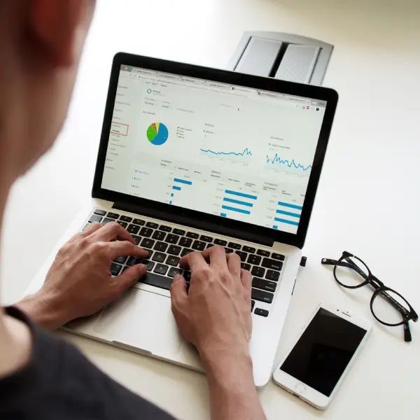 A person working on a laptop which is displaying charts and graphs