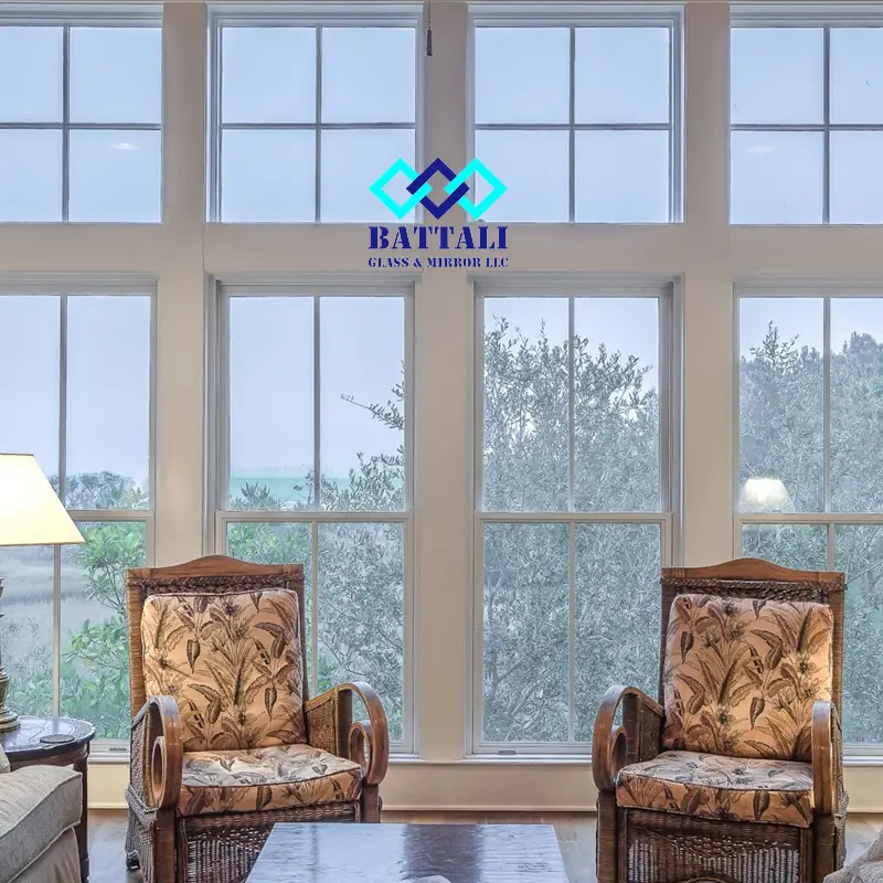 Two sofa seats in front of large glass windows