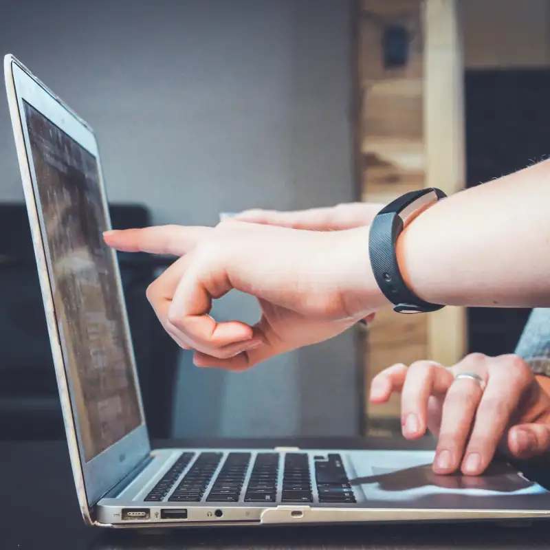 A person's finger pointing on a laptop screen